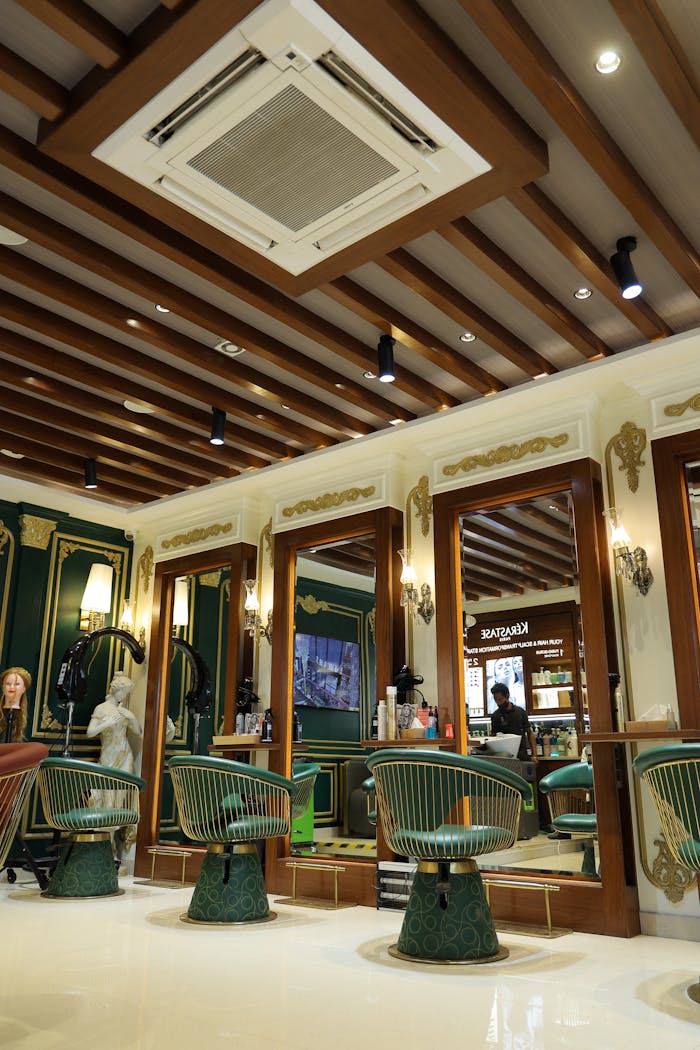 Home Luxurious hair salon with stylish green and gold decor, mirrored styling stations, and vibrant lighting.