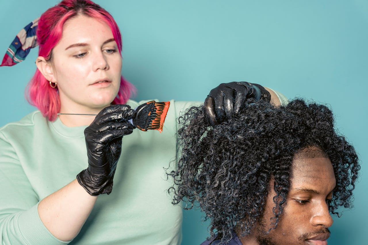 The Art of Drawing Readers In: Your attractive post title goes here Hairdresser applying dye to client's curly hair, showcasing professional hairstyling skills.