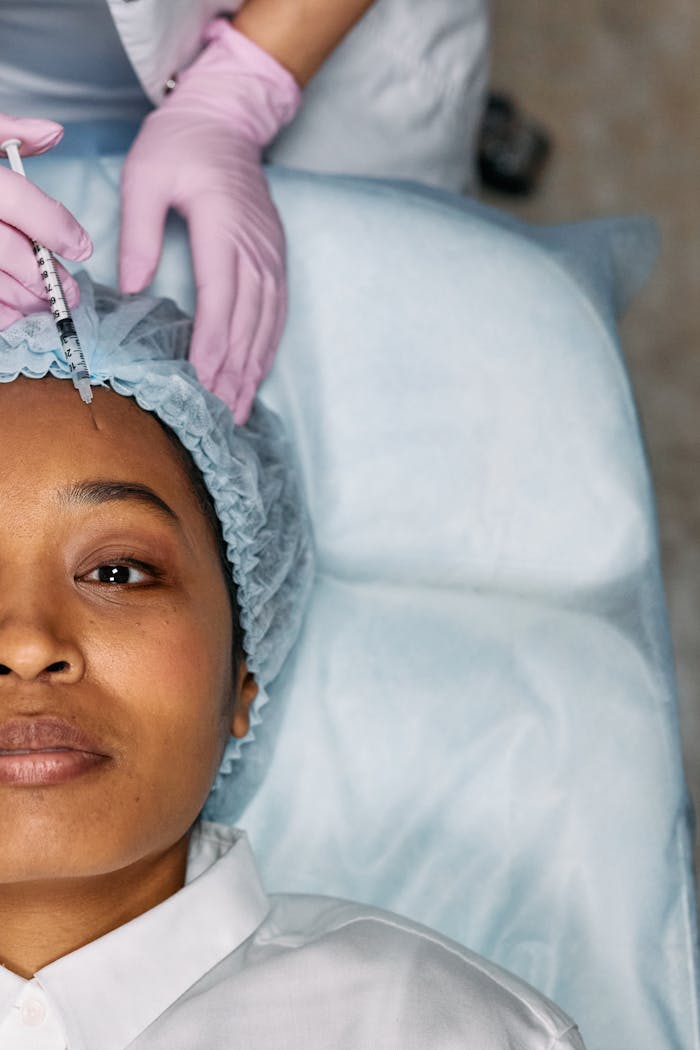 About A woman receiving a cosmetic forehead injection in a clinical setting.