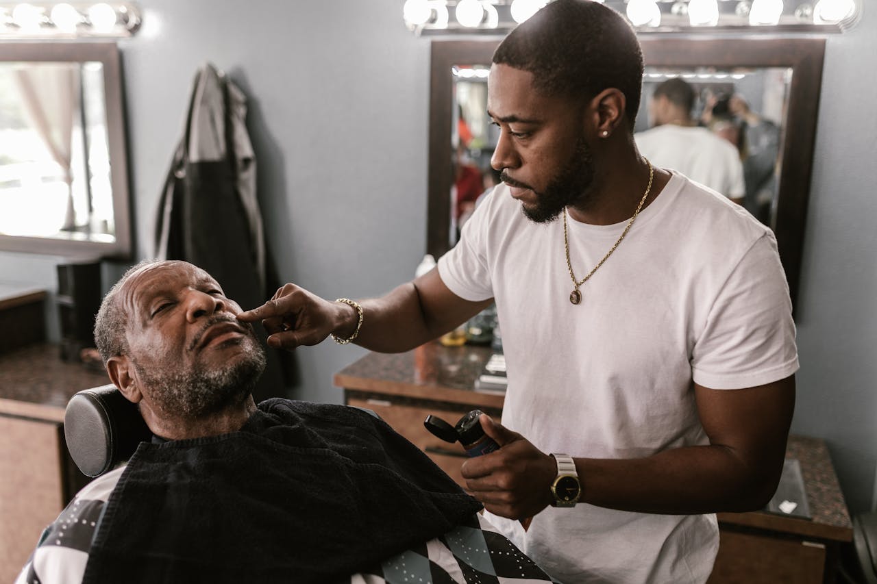 Services A barber expertly trims an elderly client's beard in a stylish barbershop.