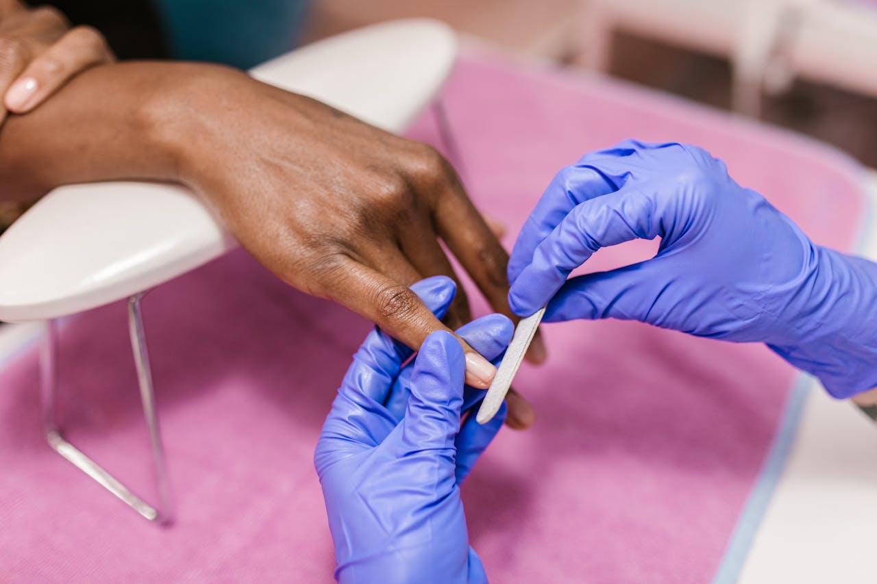 Services Close-up of hand receiving a manicure with latex gloves, showcasing precision and care.